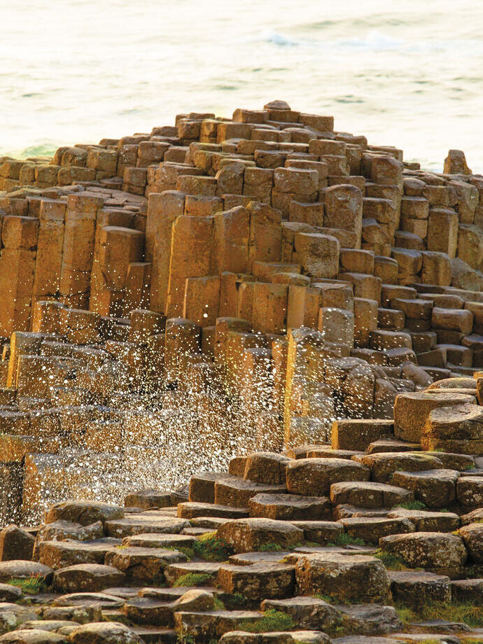 Man and child sitting on rock formations by the sea