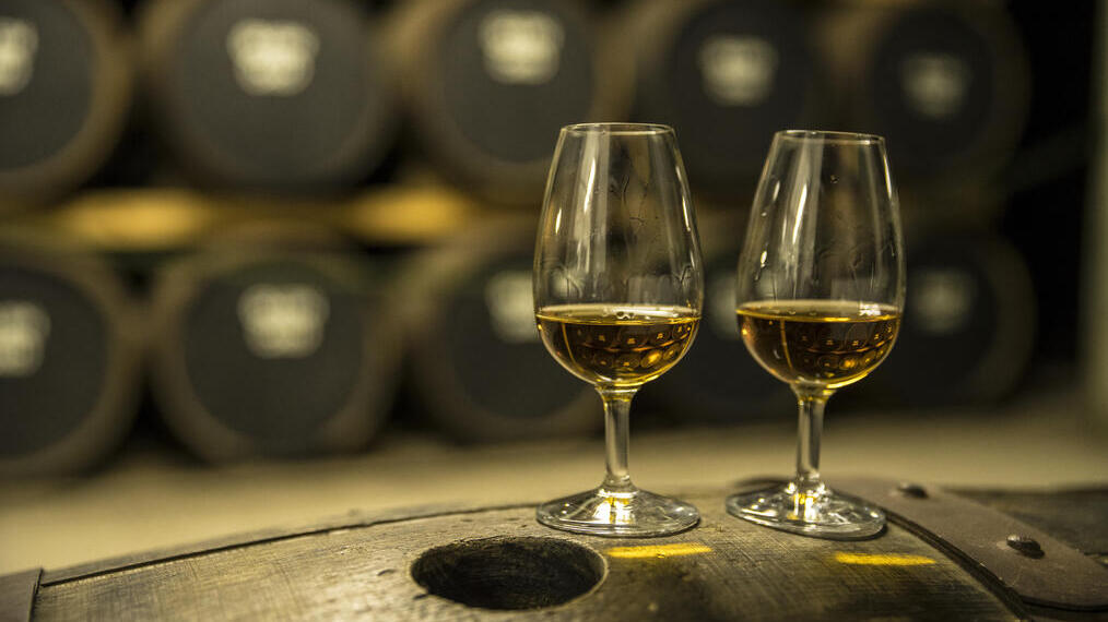 Dos vasos de whisky sobre un barril de roble