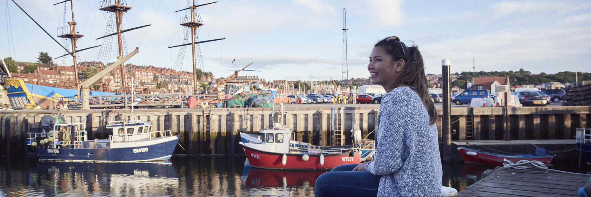 Donna sorridente seduta su un molo in un porto