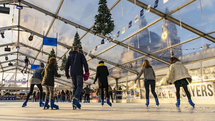People ice skating on a skating rink under a glass ceiling