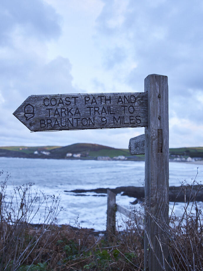 Signpost on the coastal path. Dramatic clouds and seas