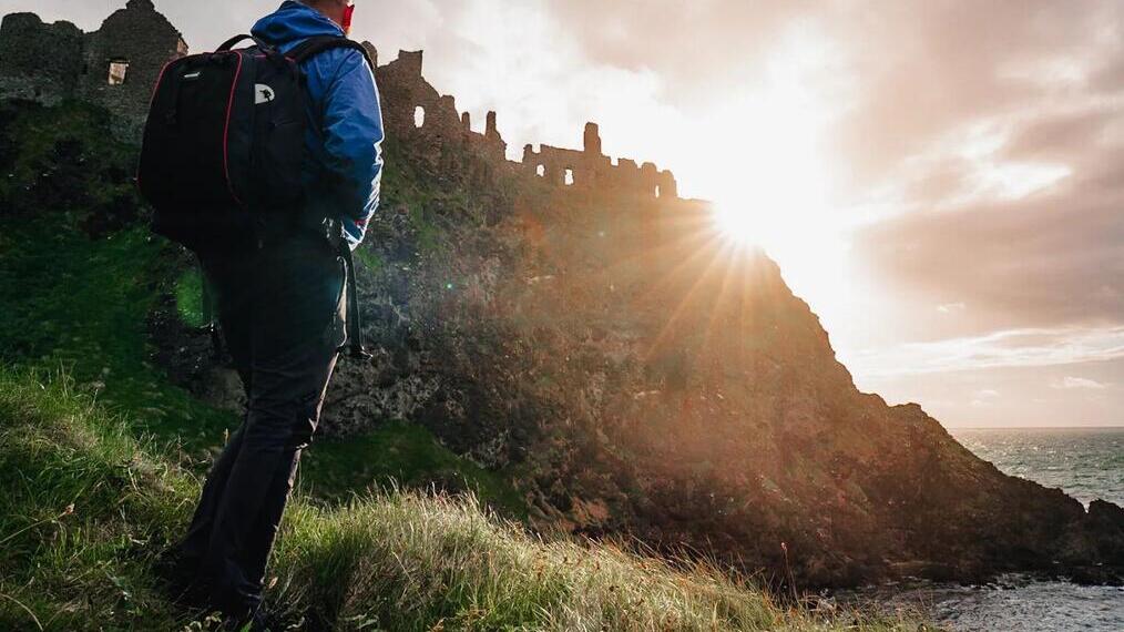 Man walking up hillside as the sun goes down