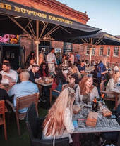 People sat at outside tables drinking at a bar in the evening
