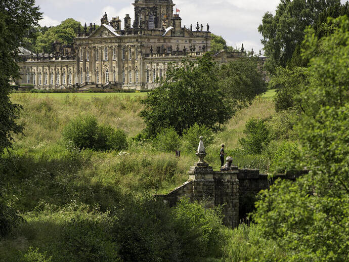 Large country house surrounded by trees with stream in the foreground