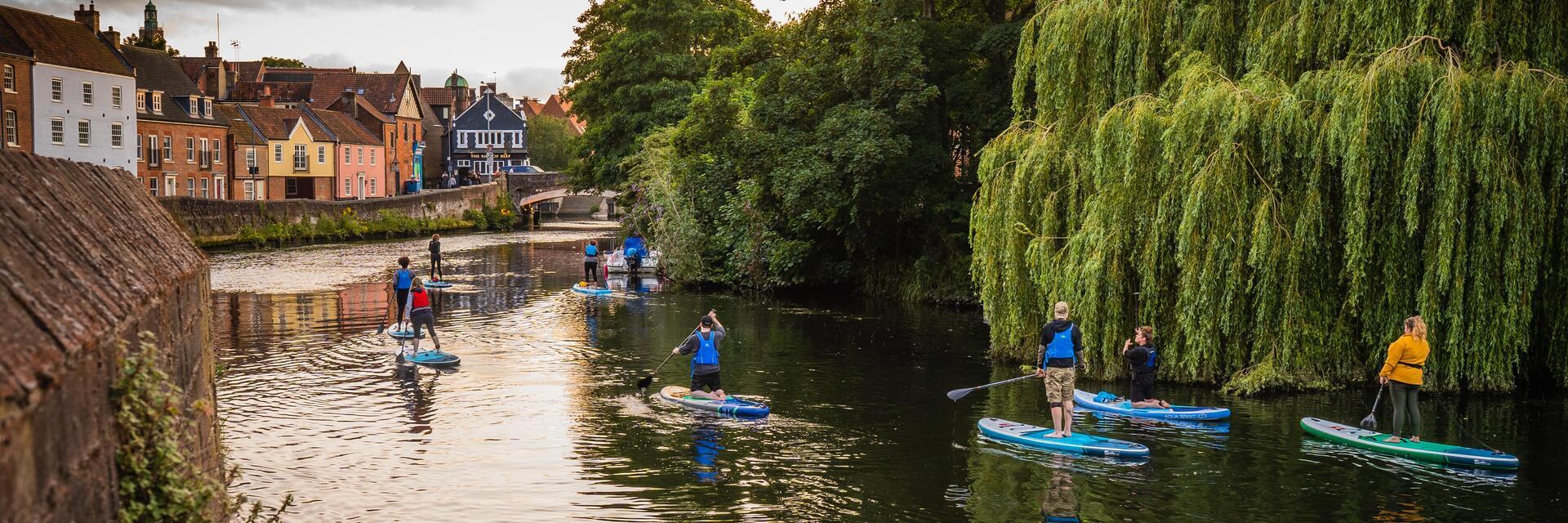 Un gruppo di persone che fa paddleboarding sul fiume Wensum