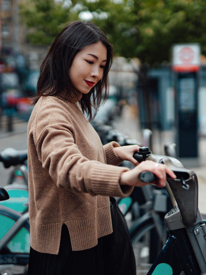 Jeune femme asiatique louant un vélo auprès d'un service de vélos en libre-service