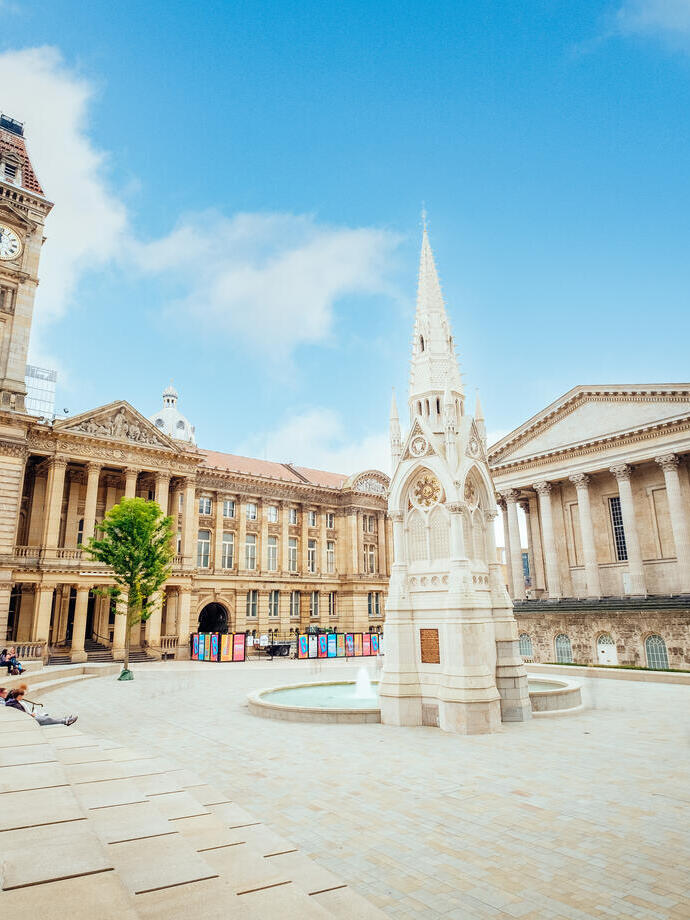 Historical building, with a clock tower, beside a fountain