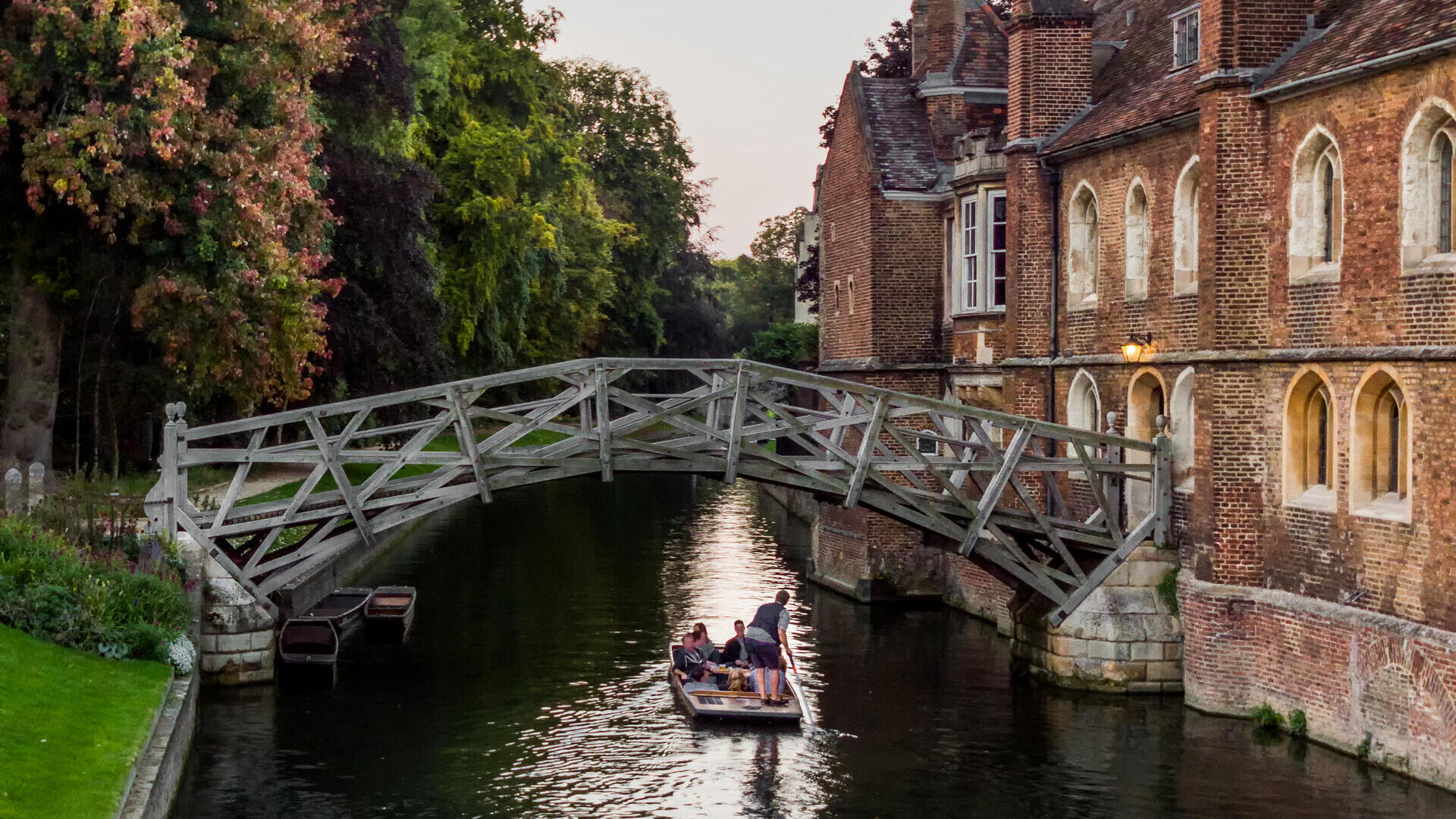Una singola barca a remi passa sotto il ponte Mathematical, in Silver Street, Cambridge, in una tarda serata estiva