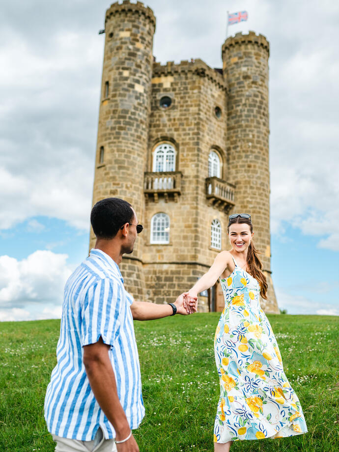 A man and a woman walk hand in hand in front of a heritage buiding