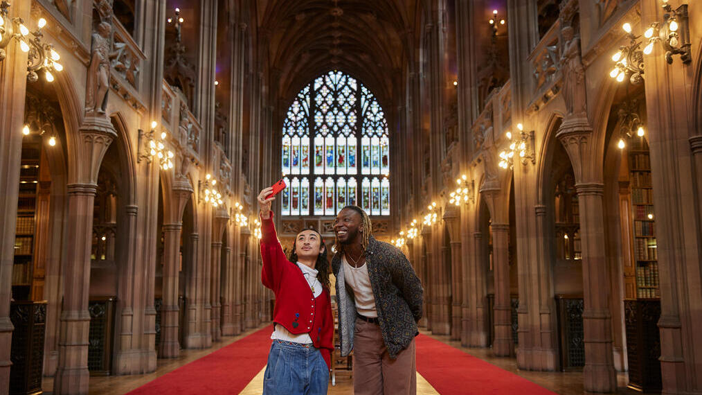 Two men taking a selfie inside a large library.