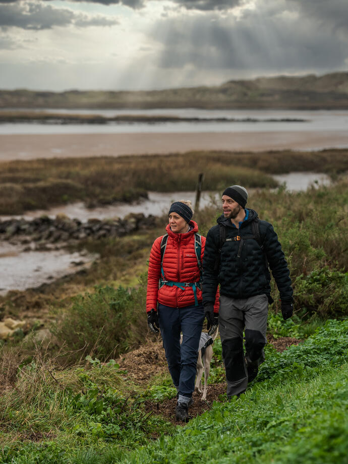 Two people walking down a hill near Burnham Overy Staithe