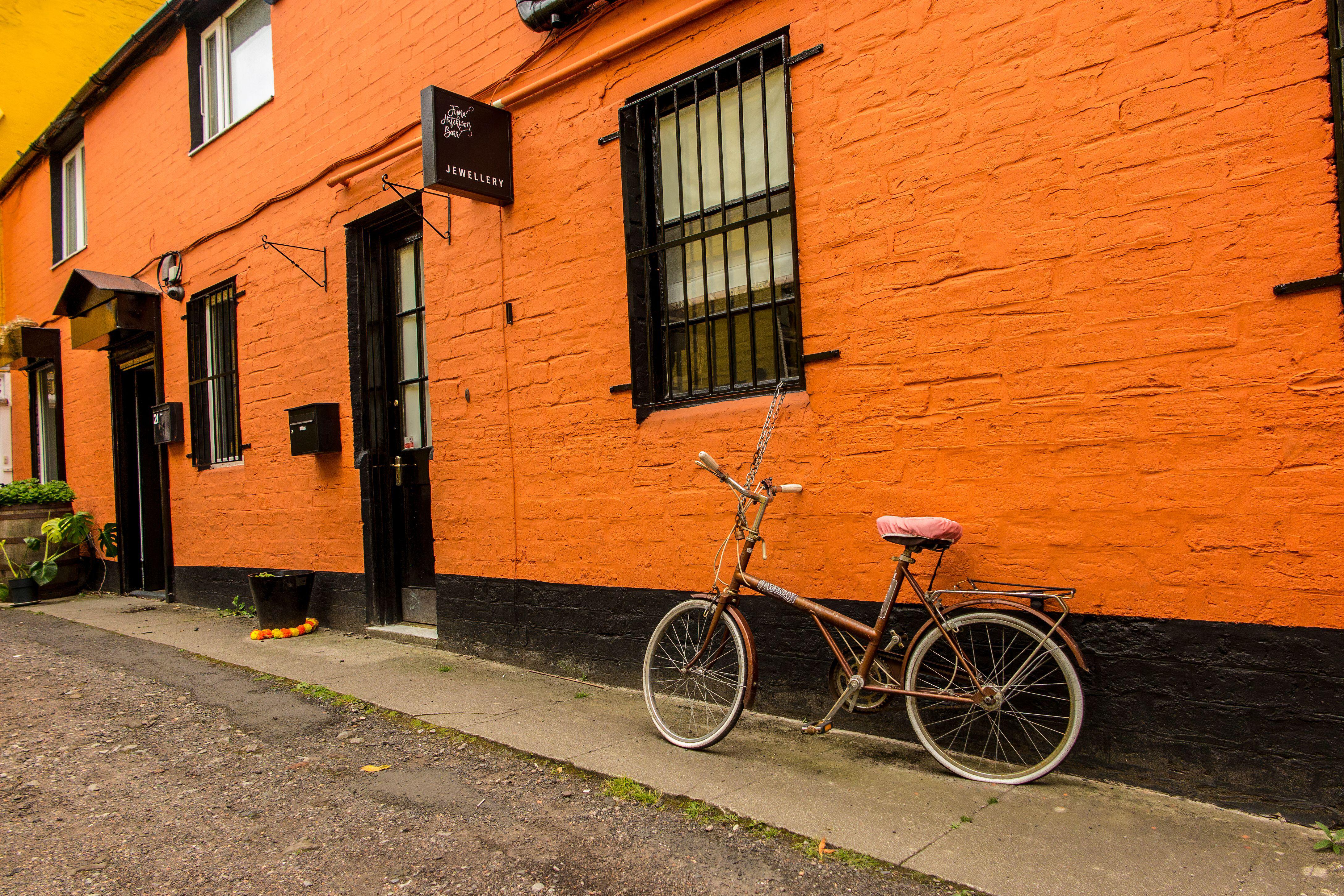 Bicycle parked outside jewellery boutique with orange painted wall in the Hidden Lane, Glasgow.