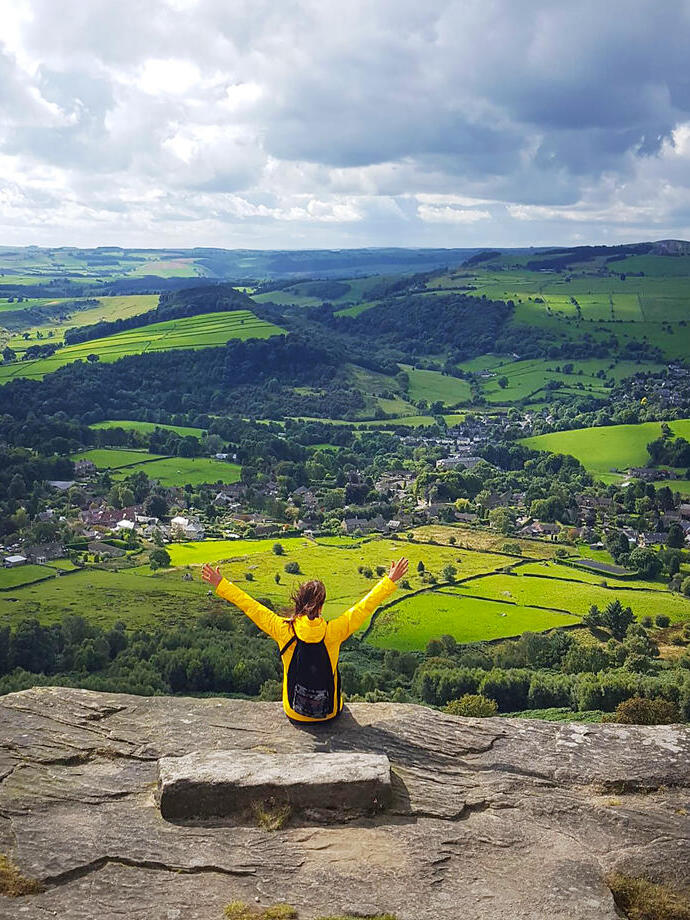 Una mujer con los brazos levantados disfrutando de la vista desde lo alto