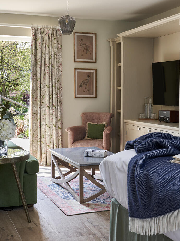 An internal view of a bedroom with bed, settee and patio doors at a countryside 18th century hotel.