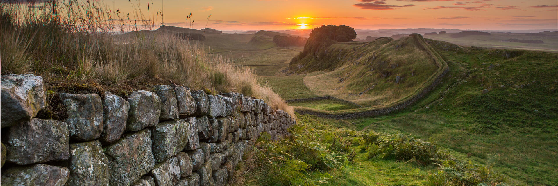 View along long stone wall over the fields at sunset