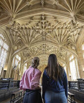 Two women look up towards an ornate ceiling