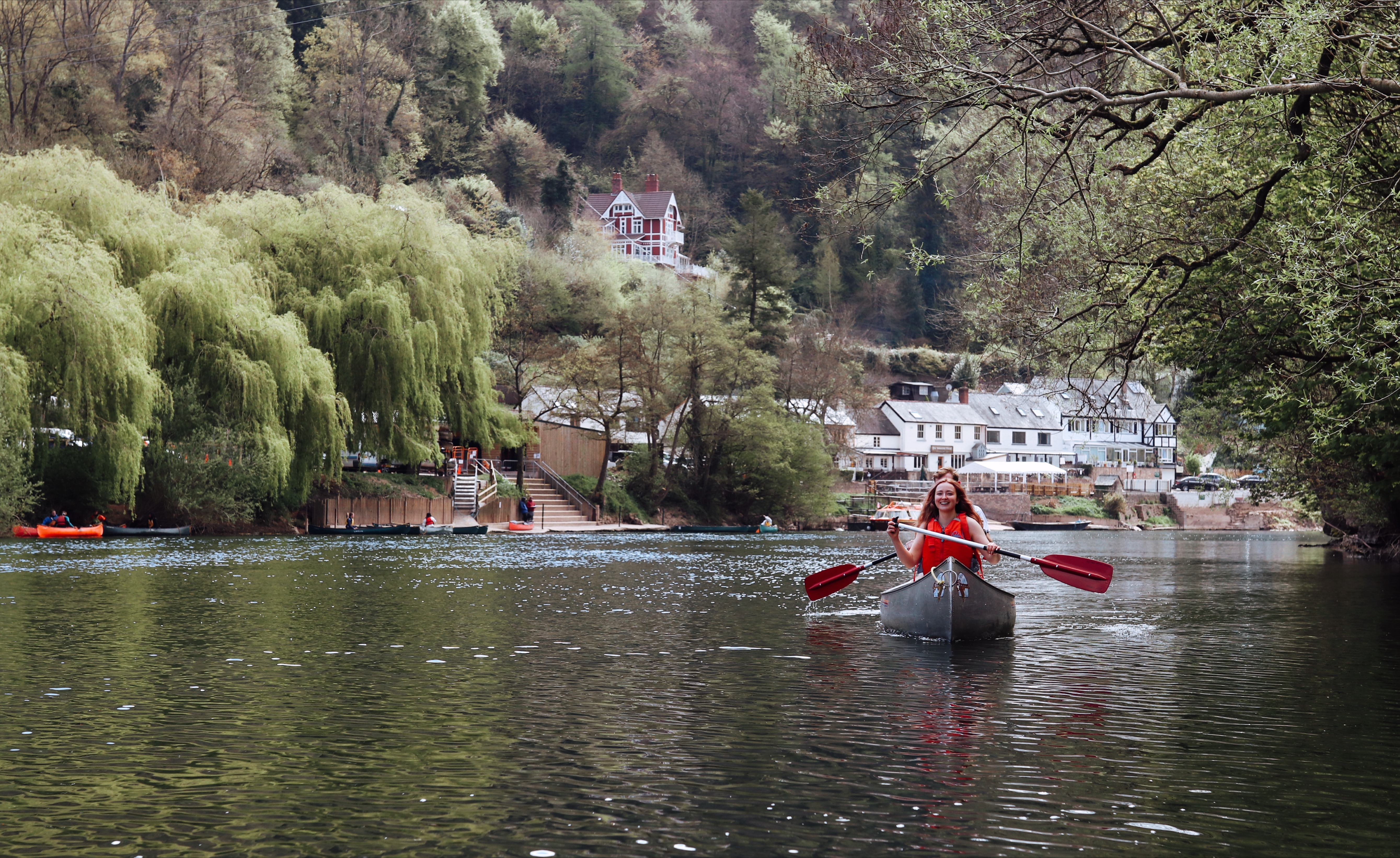 A woman in a canoe with hills and buildings behind