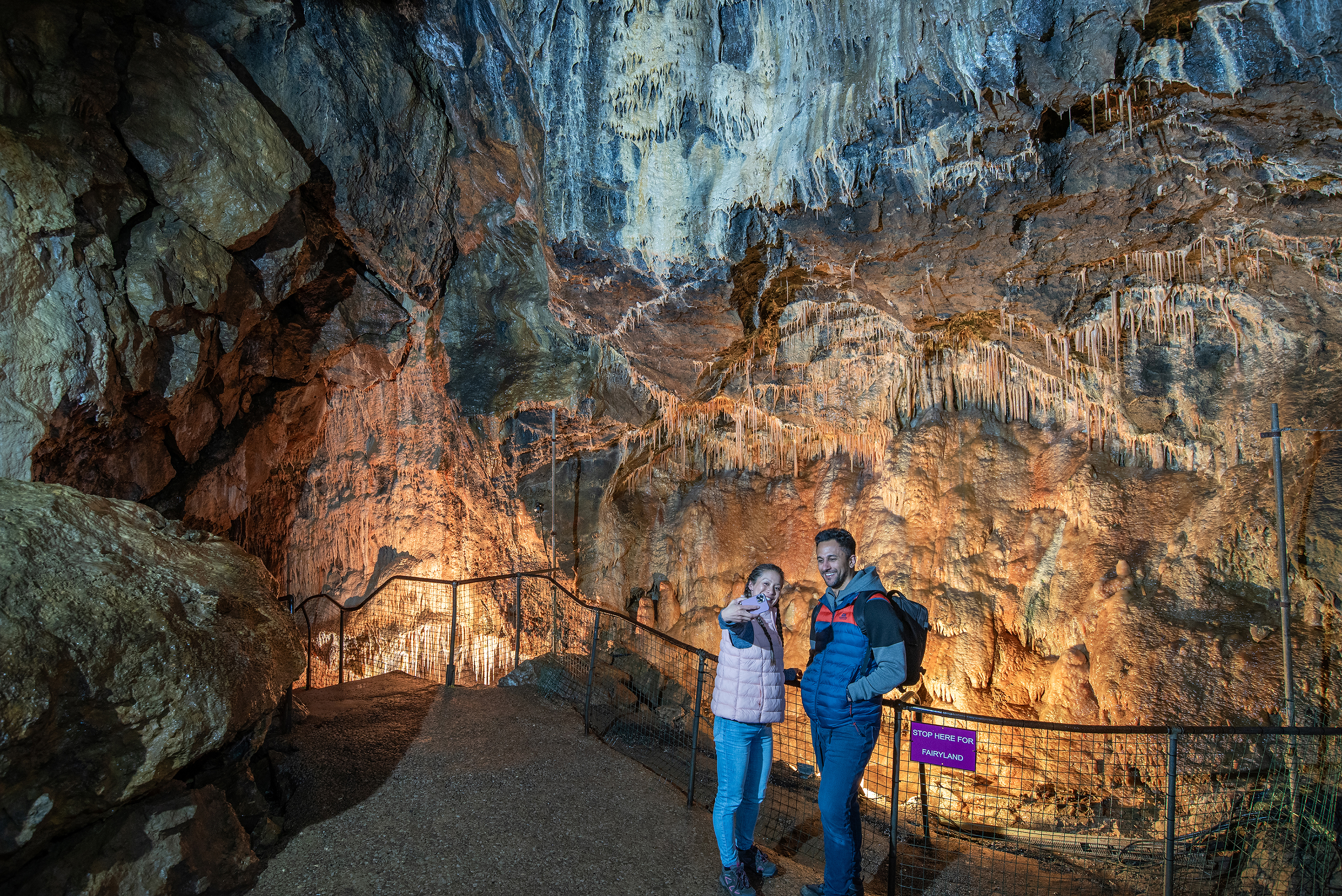 A man and a woman take a selfie with a phone in a cavern