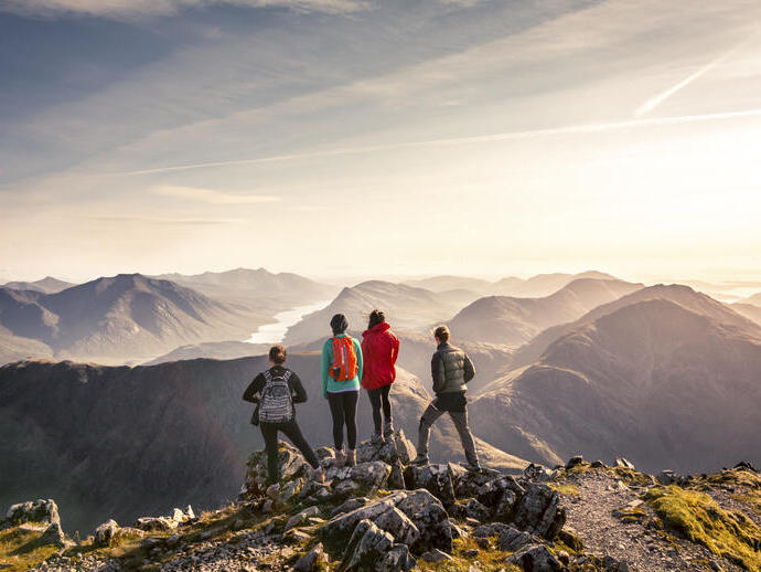 Un groupe de personnes debout sur un point élevé admirant la vue sur les montagnes en contrebas
