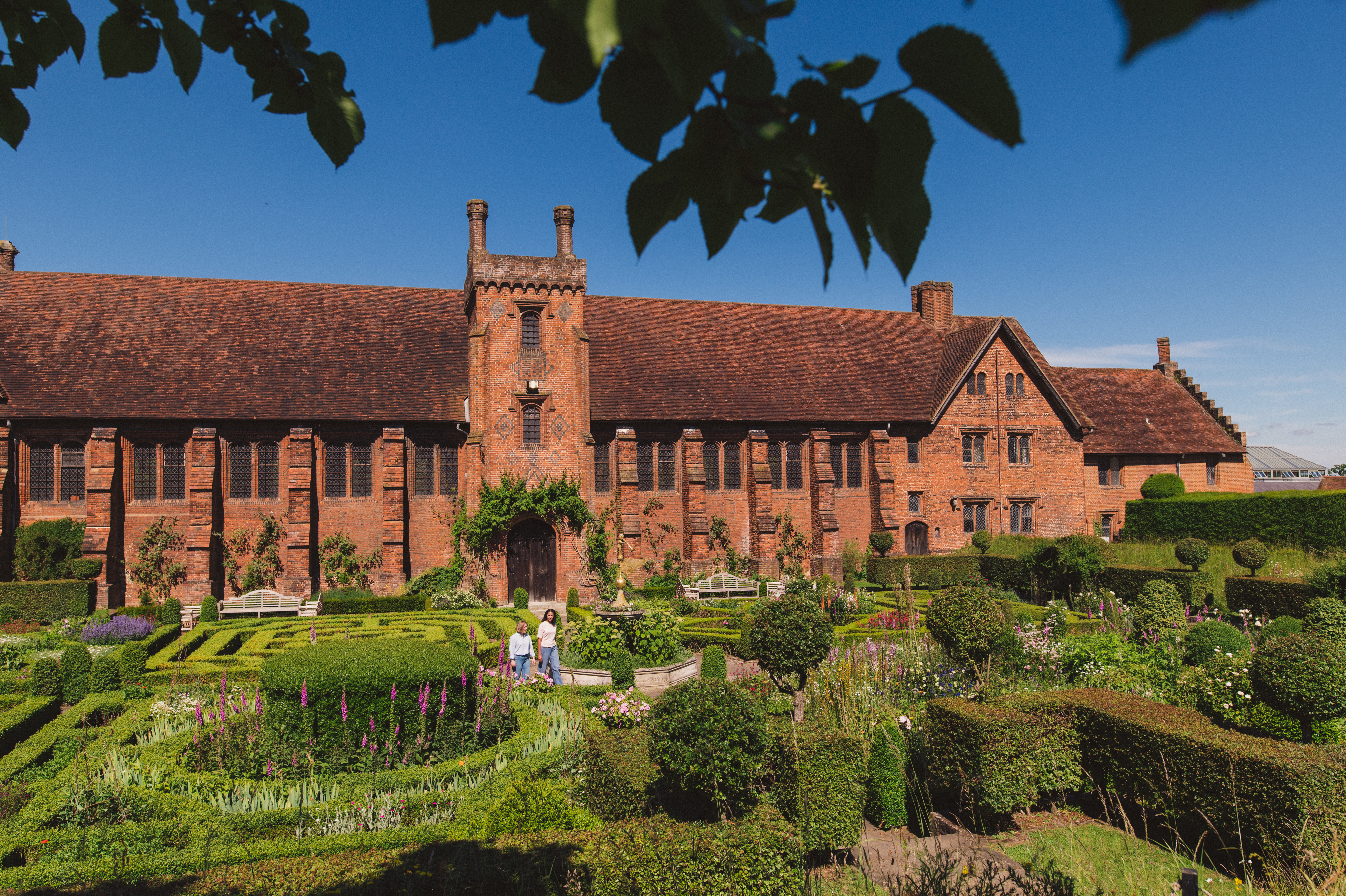 Two women walk through the gardens of a heritage house
