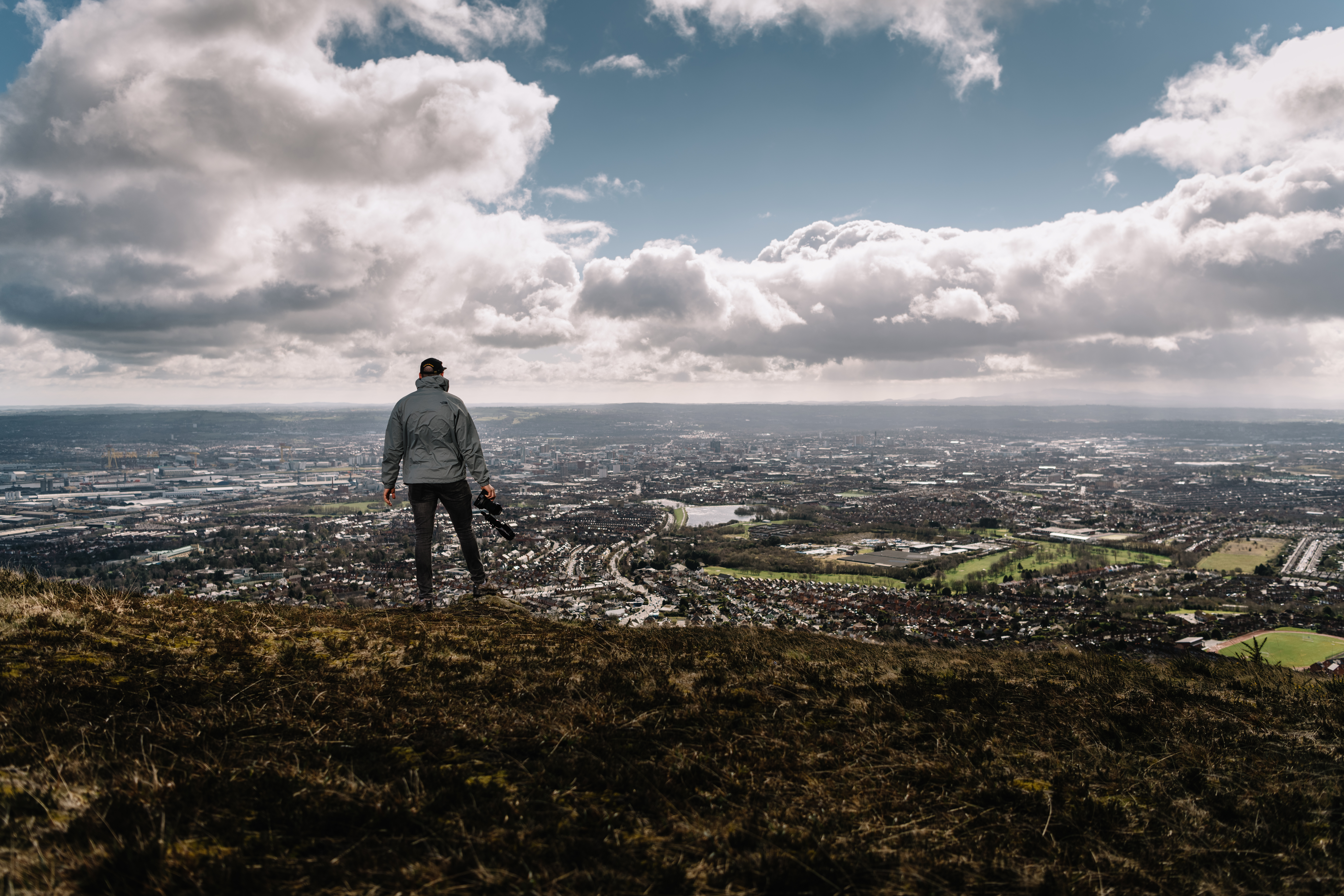 A man standing a hilltop overlooking city