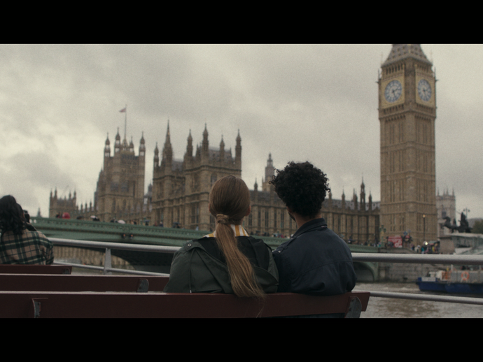 A group of people take a trip on a river boat with the Houses of Parliament beyond