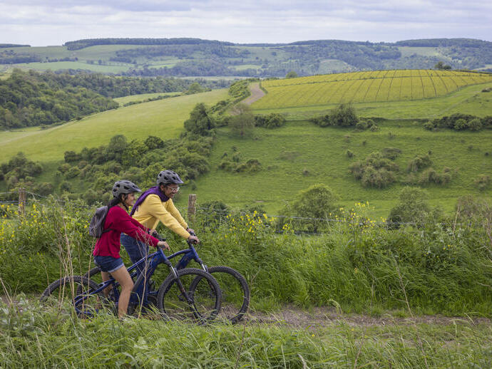A man and a woman stand with bicycles wearing helmets