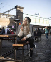 Une femme assise sur un banc, souriante, tenant une sucette