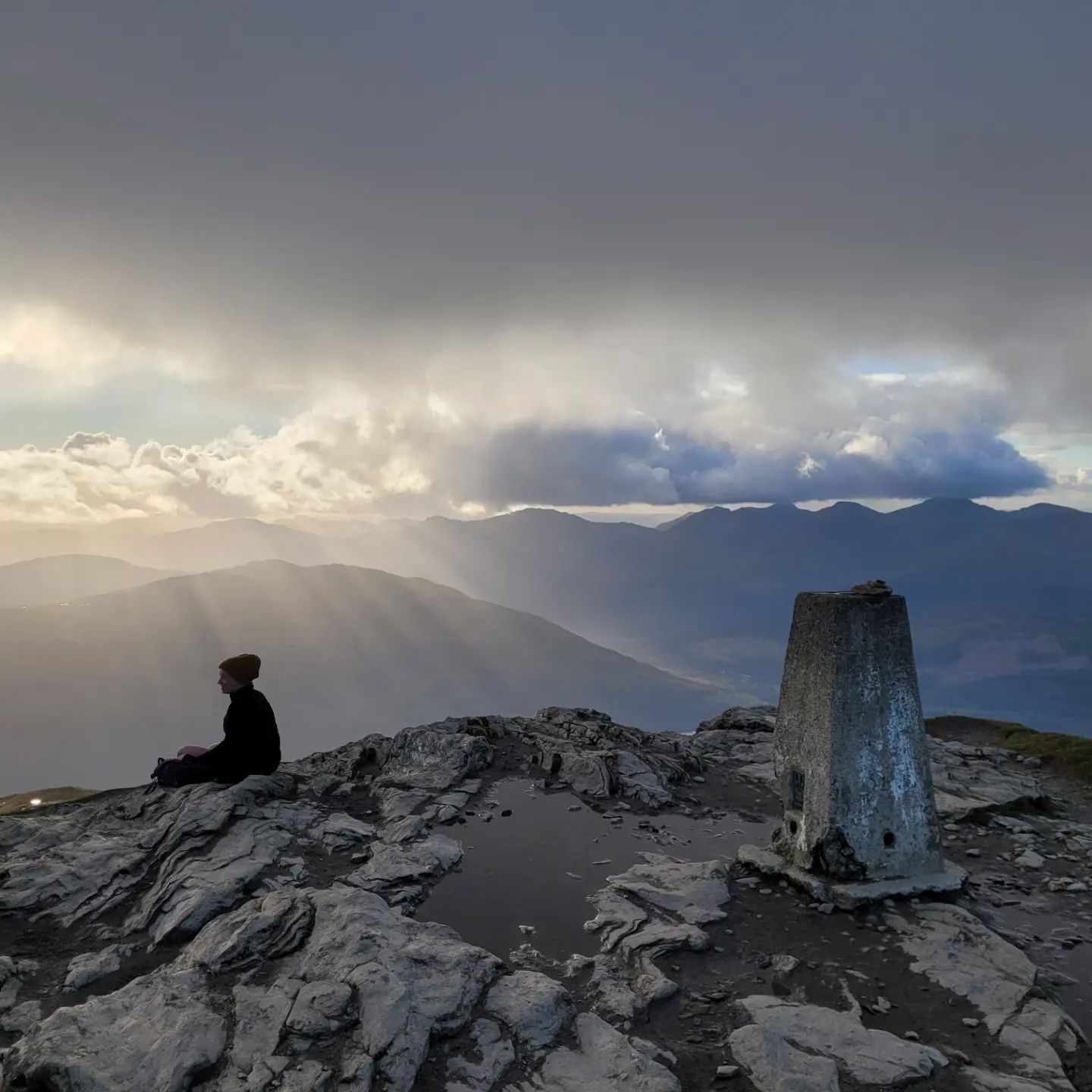 A man sitting at the top of Ben Lomond mountain