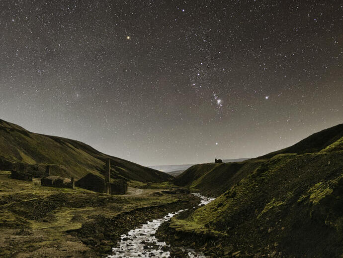 A stream winding through the mountains under a starry sky.