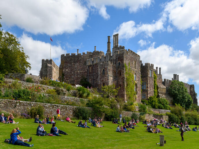 Crowds enjoying a sunny afternoon on the grounds of a castle.