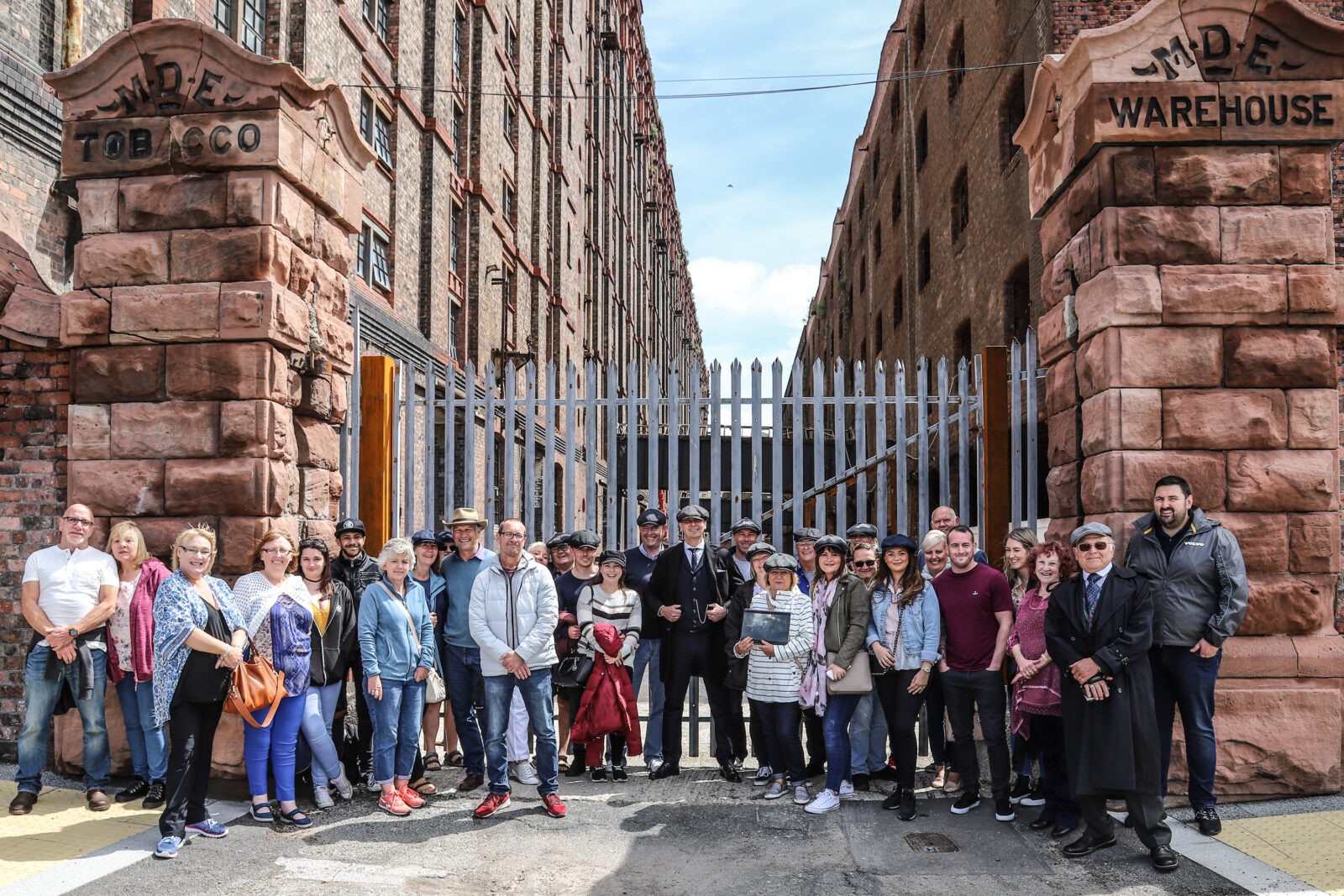 Un grupo turístico de Peaky Blinders posando fuera de un almacén industrial en Liverpool