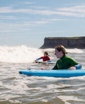Deux femmes tenant des planches de surf en attendant les vagues dans la mer