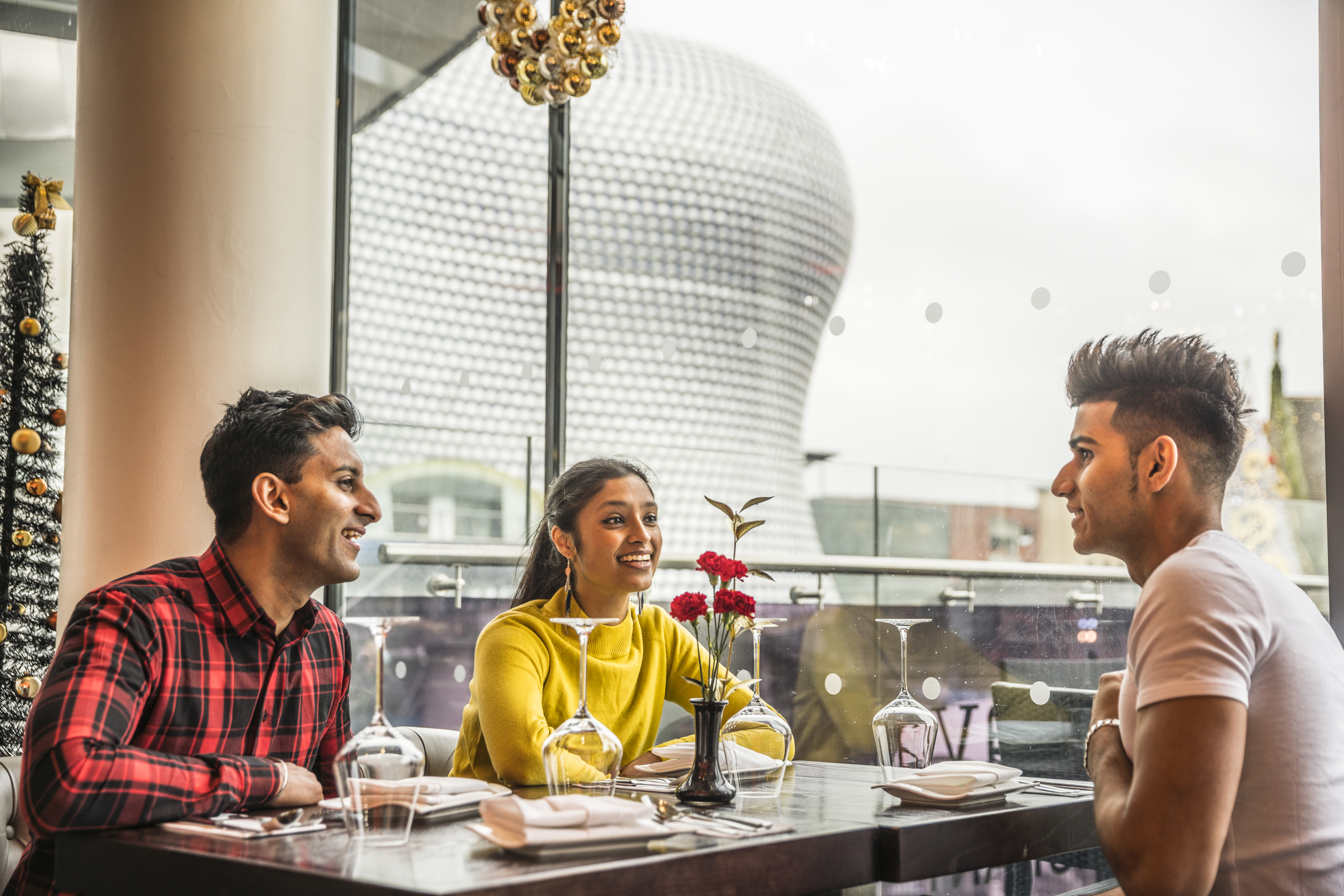 Three young people sat at a dining table with high views