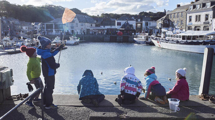 Bambini seduti sul molo del porto che pescano granchi