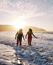 Open water swimmers by the shore at sunset.
