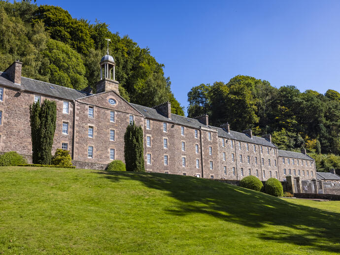 A historic four-storey mill building on a sunny day.