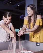 Frau und Kind spielen an einer interaktiven Ausstellung in einem Museum