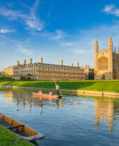 People punting along a river next to a college and chapel.