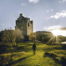 Man walking towards a castle at sunrise