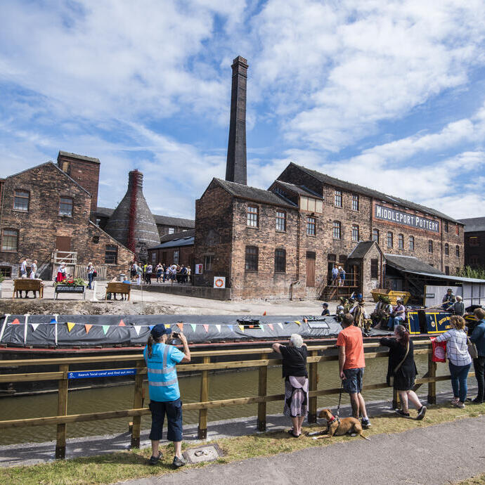 A group of people looking across the Trent and Mersey Canal at several historic buildings in Stoke