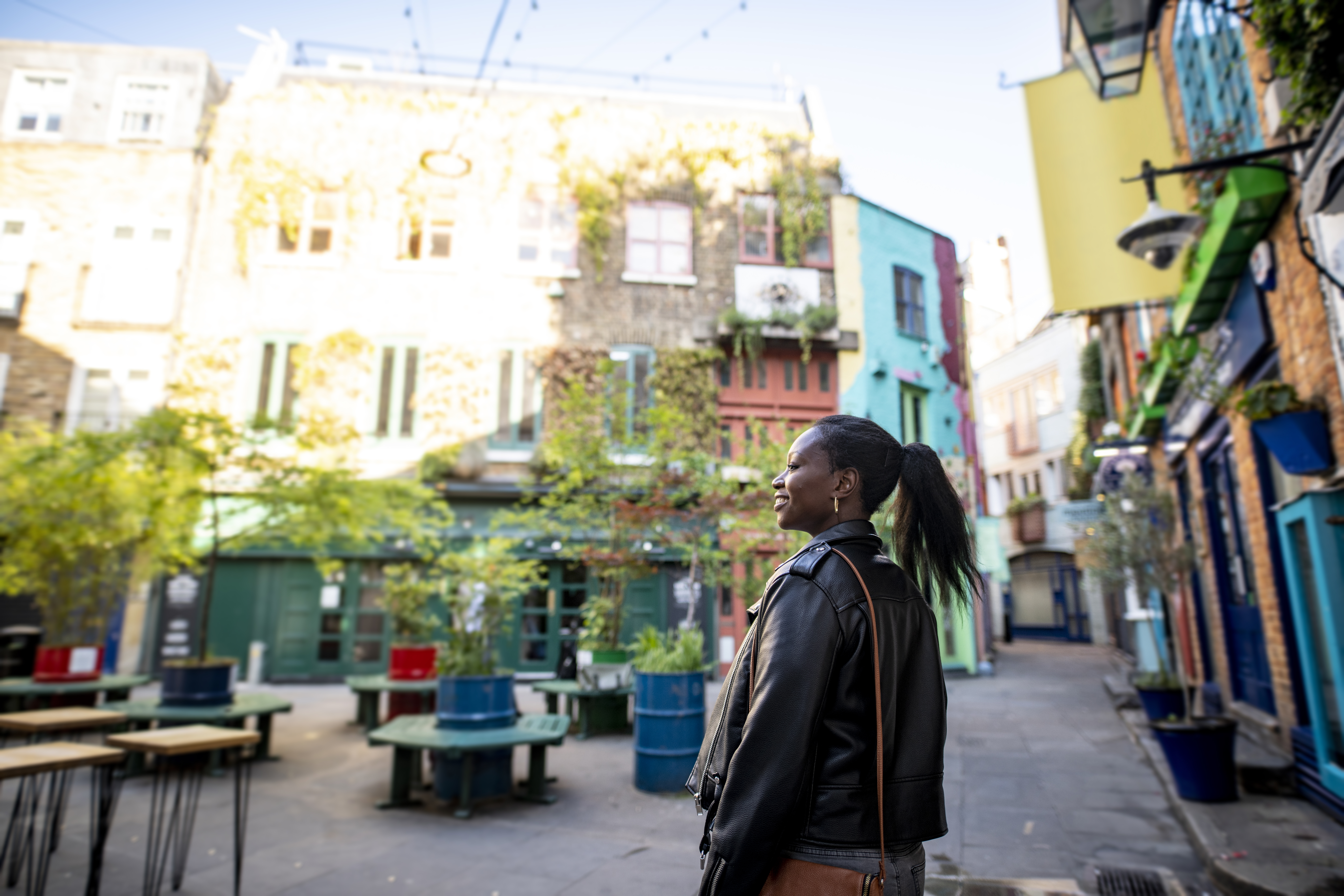 Female tourist exploring a London shopping courtyard with shops and outdoor seating.