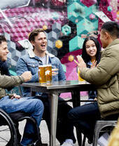 Friends, including a man in a wheelchair having a beer in outdoor beer garden