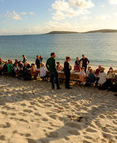 People sitting at a table on the beach, Isles of Scilly