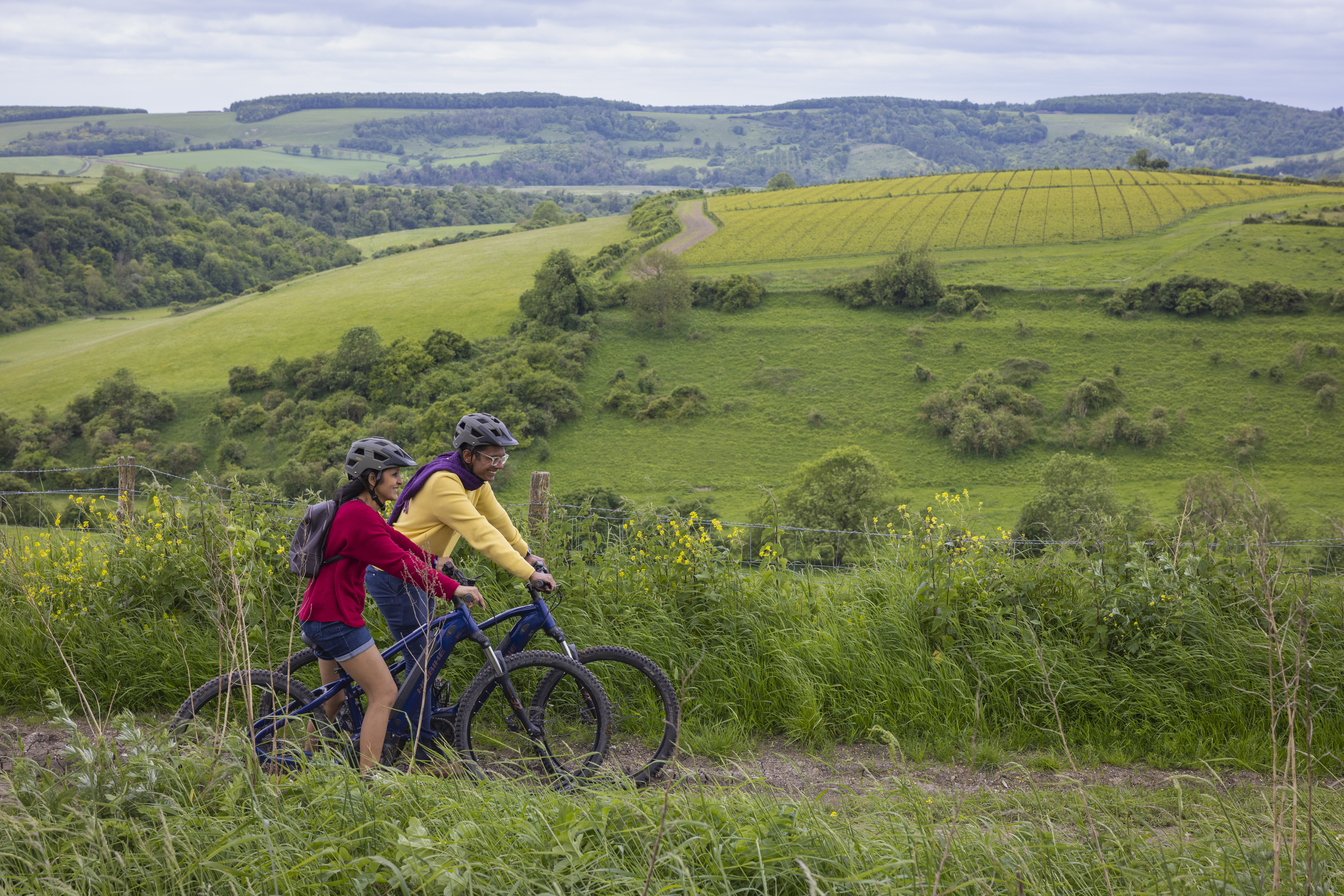 A man and a woman stand with bicycles wearing helmets