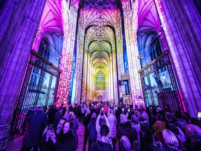 Group of people looking and photographing light show in a cathedral