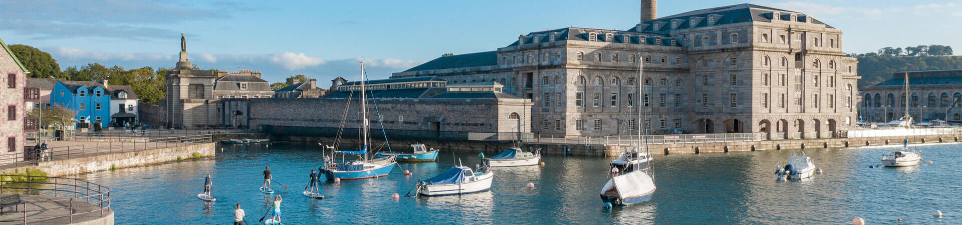 People paddleboarding near a dock in Plymouth
