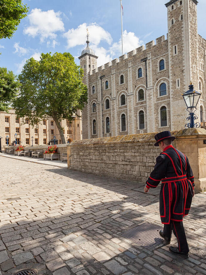 Beefeater walking by the Tower of London on a sunny day