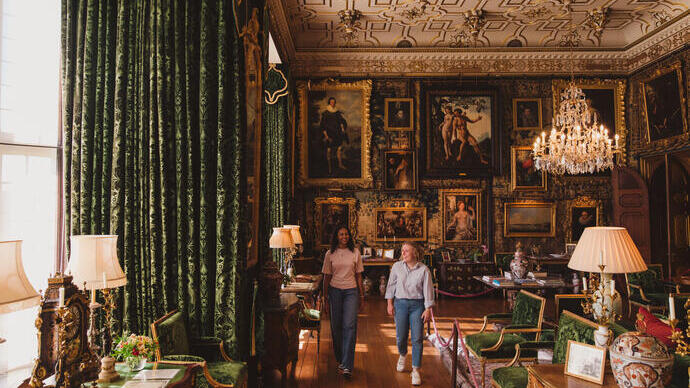 Zwei Frauen spazieren durch einen prunkvollen Raum in einem historischen Haus