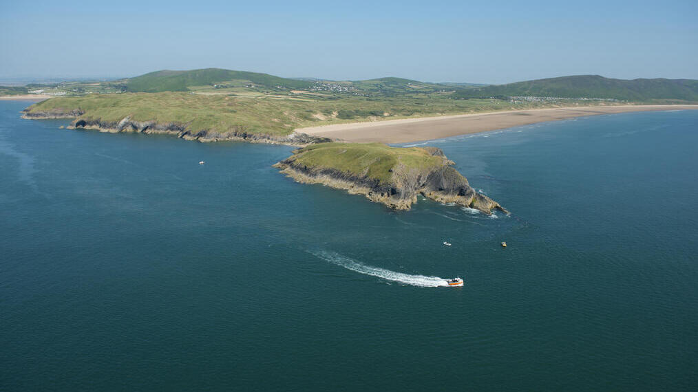 زورق سريع في البحر يتبع الساحل في مياه زرقاء عميقة